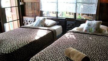 A room with two beds, each with patterned bedding and a rolled towel on one bed.