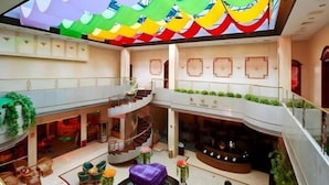 A multi-level hotel lobby with a central staircase, seating areas, and decorative plants. - Quanzhou Overseas Chinese Hotel (Quanzhou)
