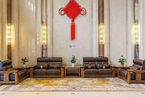 Un vestíbulo con sofás de cuero dispuestos en semicírculo, alfombra estampada y apliques decorativos de pared.