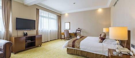 A hotel room with a bed, bedside tables, a TV, a desk, and a chair.