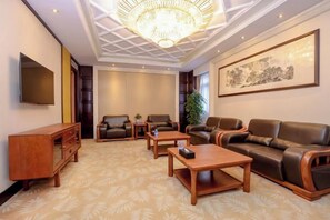 A hotel room with a large sofa, two armchairs, a coffee table, a TV, and a bookshelf. - Hongqiao Yunfeng Hotel (Shanghai)