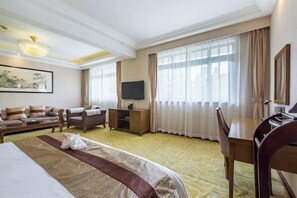A hotel room with a large bed, a desk, a chair, a television, and a sofa. - Hongqiao Yunfeng Hotel (Shanghai)