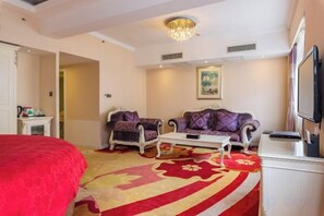 A hotel room with a large bed, two sofas, a coffee table, a TV, and a painting on the wall. - Hongqiao Yunfeng Hotel (Shanghai)