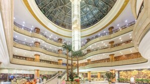 Un atrium à plusieurs niveaux, surmonté d’une coupole de verre, agrémenté de palmiers et doté d’un escalier central.