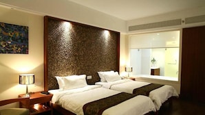 A hotel room with two beds, a large textured wall, a window with a view, and a painting on the wall. - Jin Jiang Sanya Royal Garden Resort (Sanya)