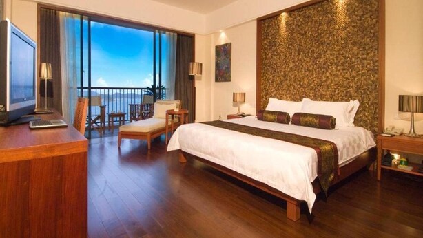 A spacious bedroom with a large bed, a desk with a laptop, a chair, and a balcony with a view. - Jin Jiang Sanya Royal Garden Resort (Sanya)