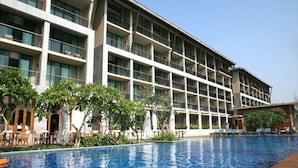 A hotel with multiple floors, a swimming pool, and outdoor seating areas. - Jin Jiang Sanya Royal Garden Resort (Sanya)
