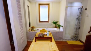 Une petite pièce agréable, dotée d’un lit en bois, d’une table de chevet, d’une fenêtre, d’un lavabo et d’un espace douche.