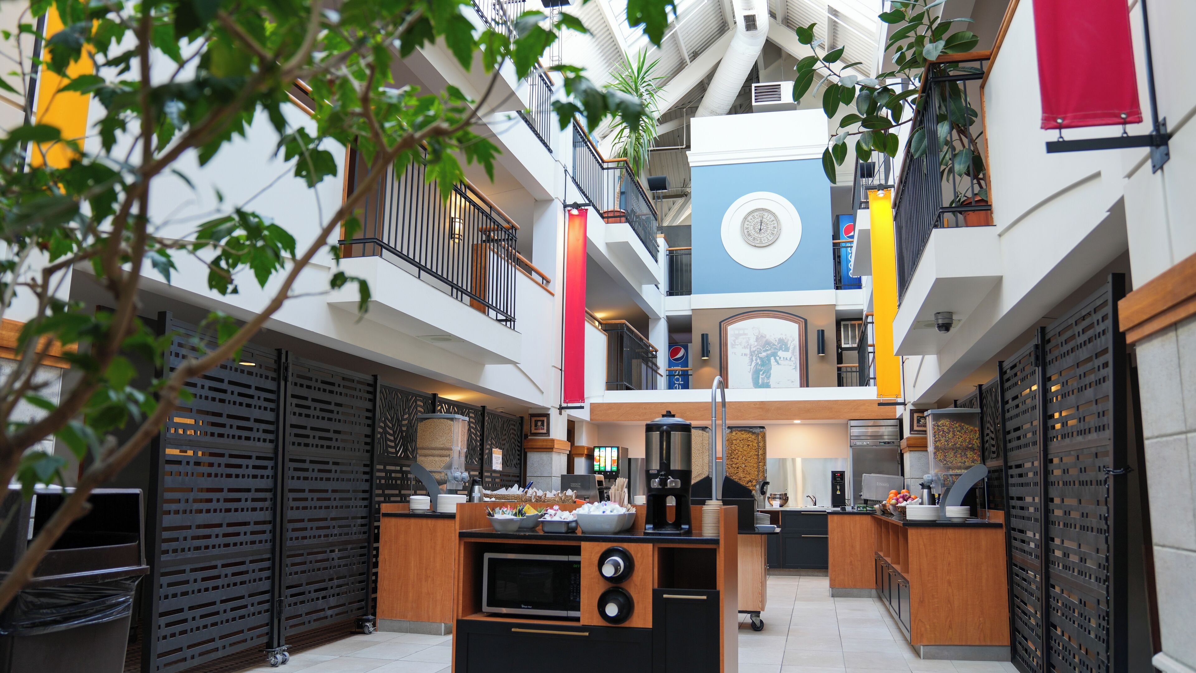 Un atrio moderno con una zona de cocina central, varios pisos y un reloj decorativo.