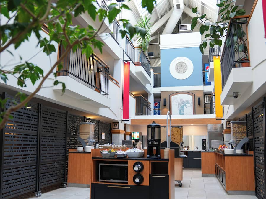 A modern atrium with a central kitchen area, multiple floors, and a decorative clock.