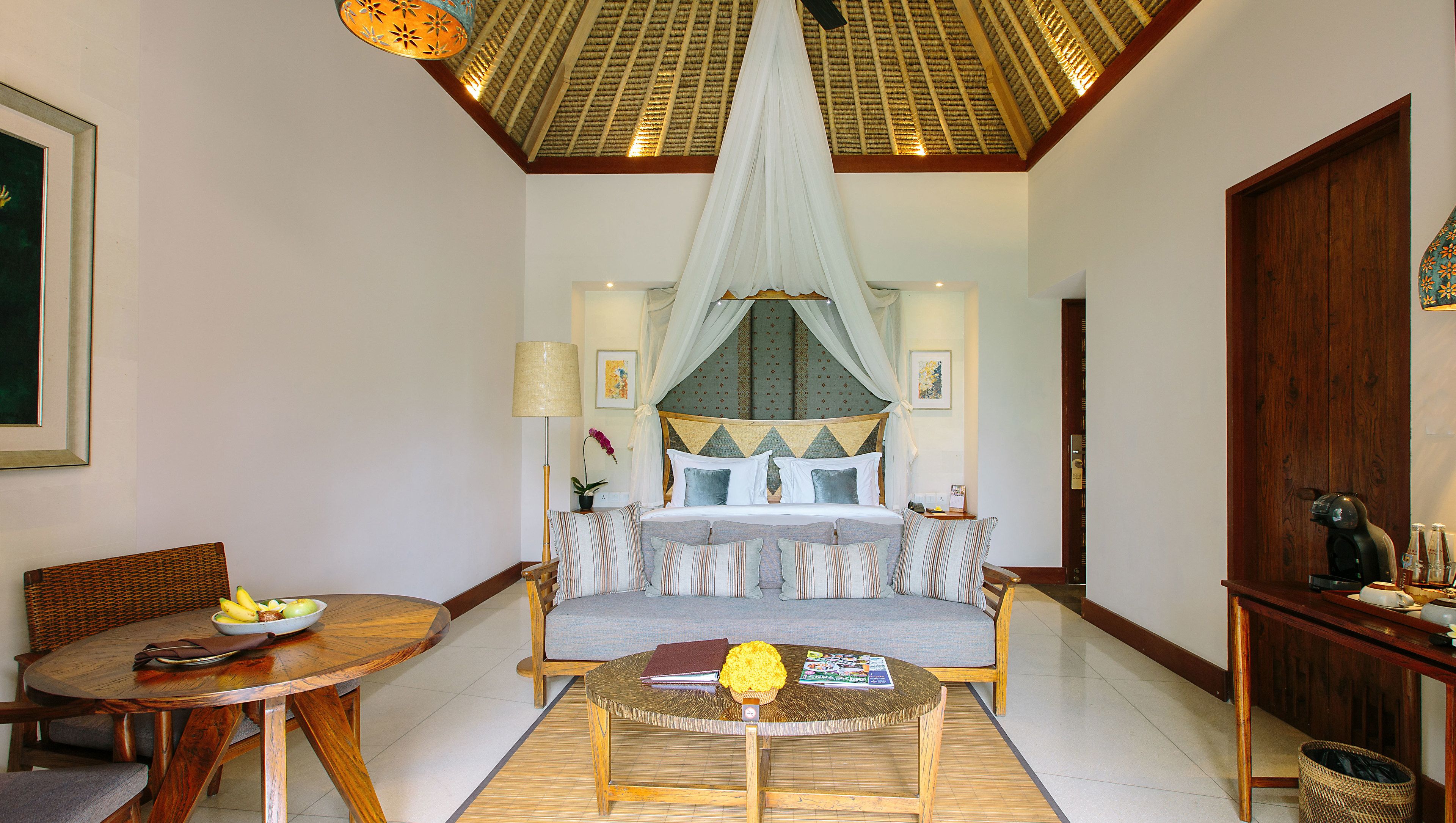 A spacious room with a large bed, a dining area with a round table, and a seating area with a sofa.