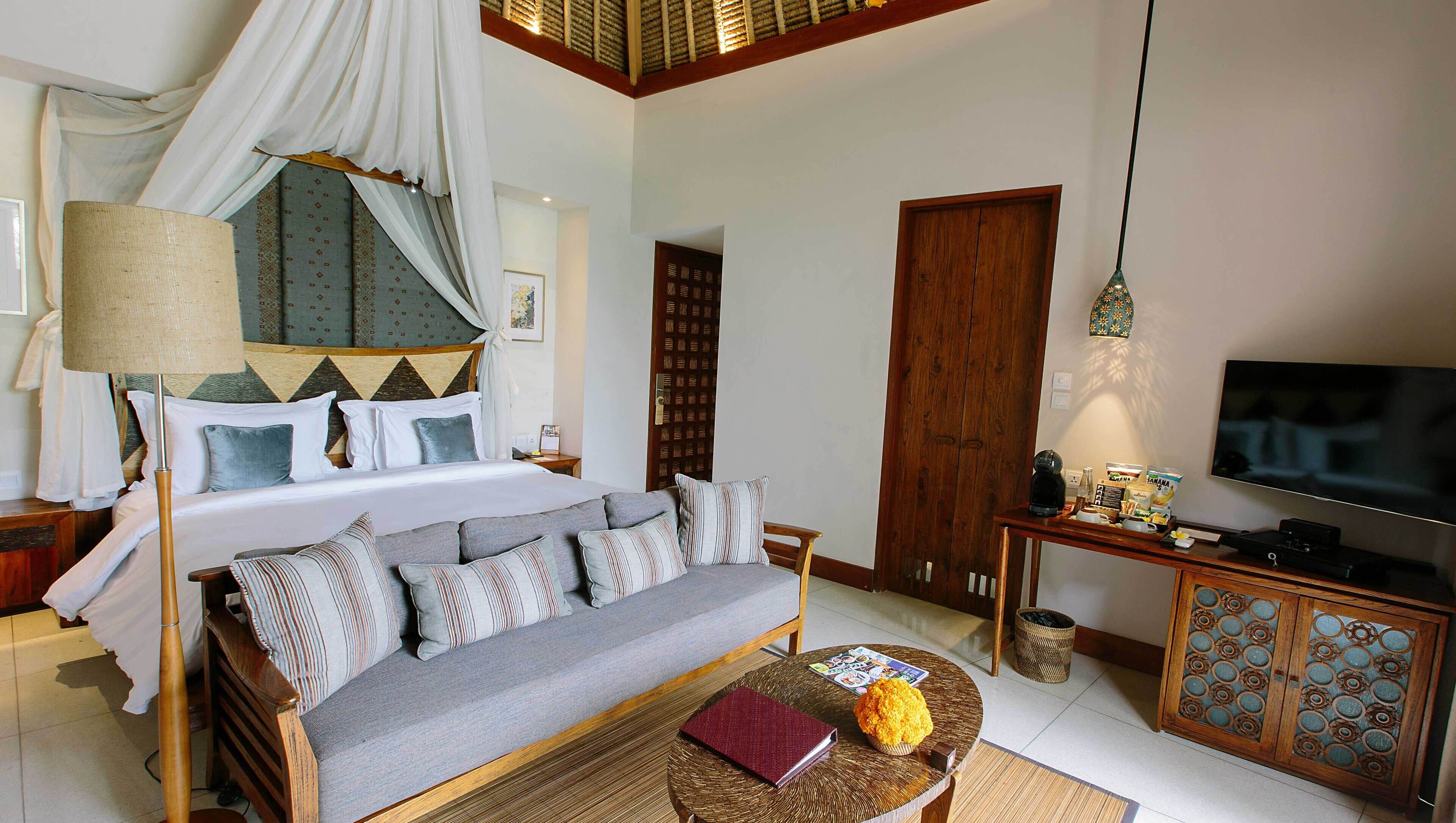 Quarto com cama, sofá, televisão e mesa de centro.