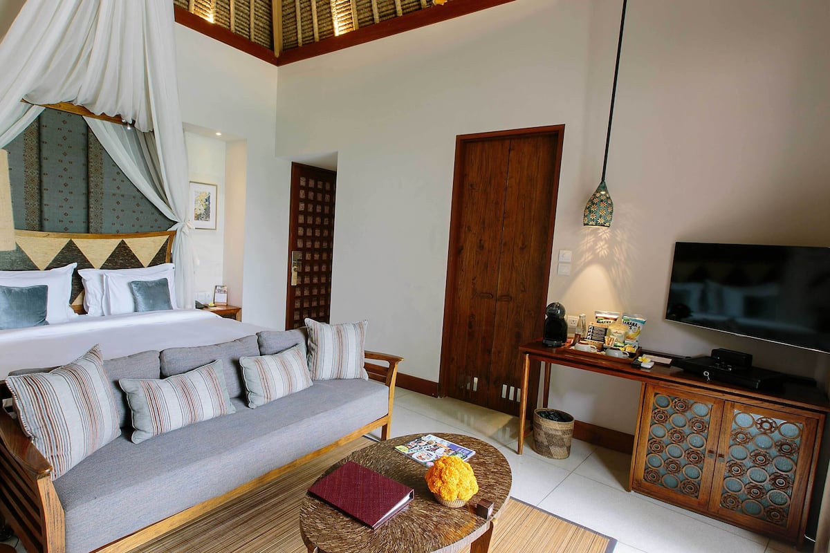 A bedroom with a bed, a sofa, a television, and a coffee table.