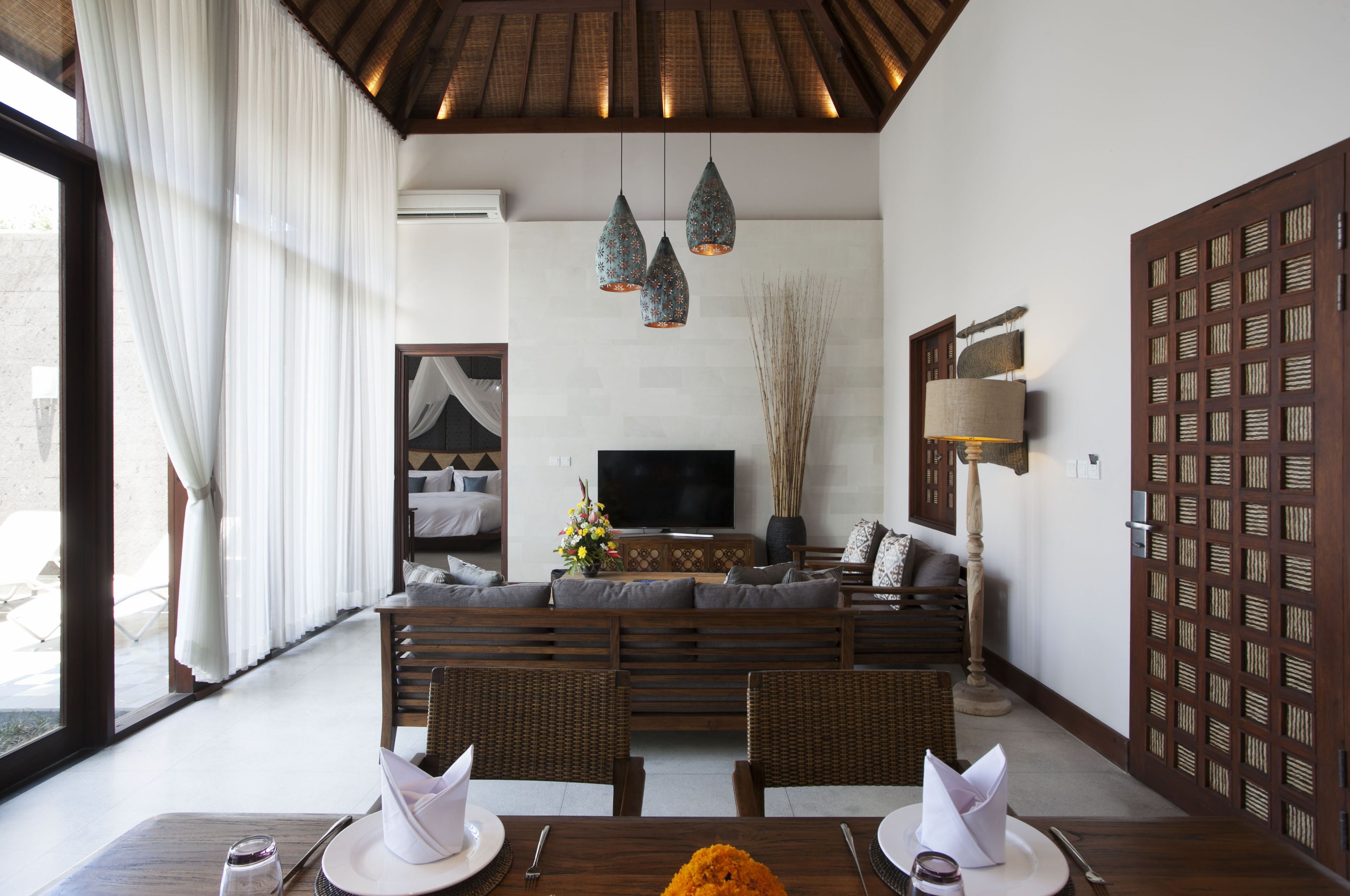 A modern living room with a sofa, dining table, and a TV.