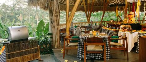 An outdoor dining area with checkered tablecloths, wooden chairs, and a grill.