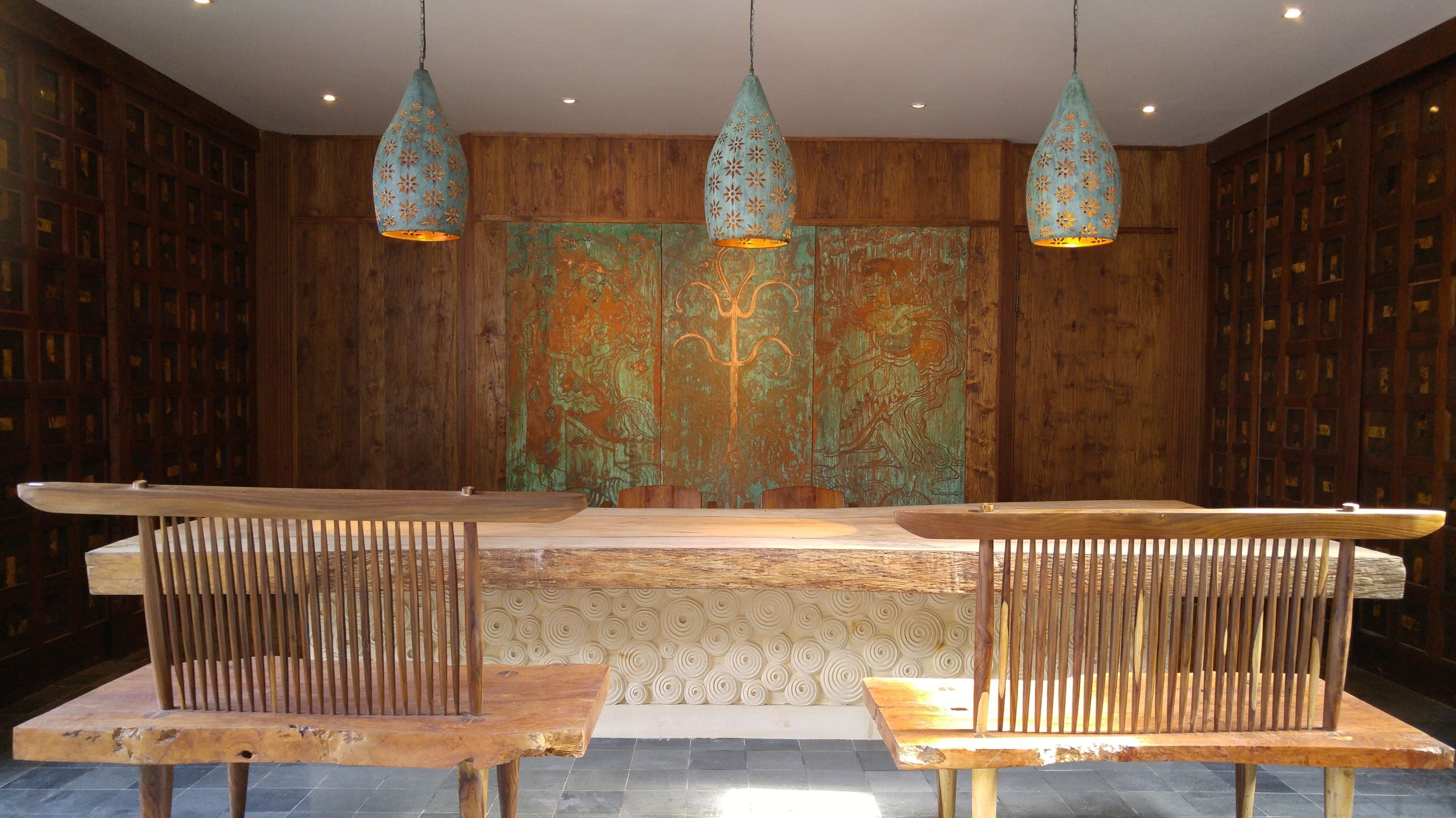 A wooden interior with three hanging pendant lights, a central bench, and a patterned wall.