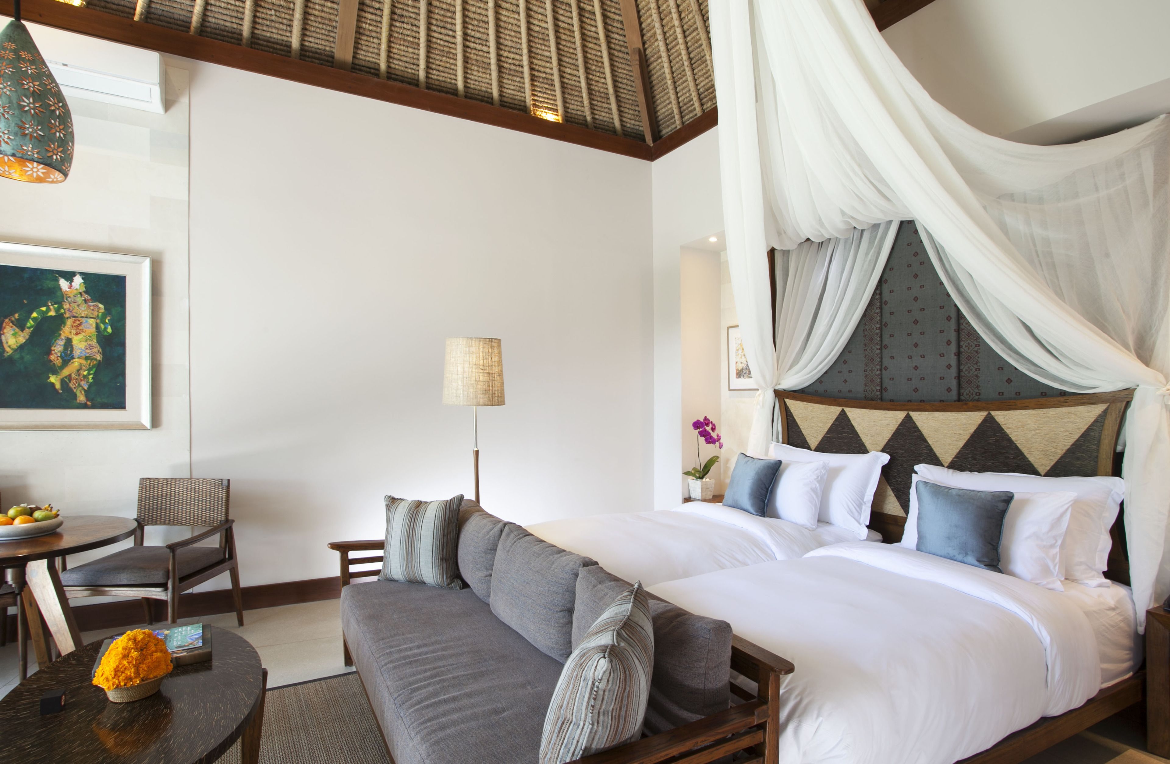 A bedroom with a four-poster bed, a sofa, a dining table, and a chair.