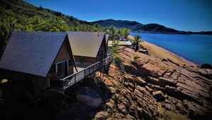 A beachfront property with a house featuring a balcony and a view of the beach and water. - Base Backpackers Magnetic Island - Hostel (Nelly Bay)