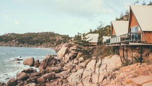 A coastal property with a wooden structure elevated on stilts, featuring a balcony and a view of the sea. - Base Backpackers Magnetic Island - Hostel (Nelly Bay)