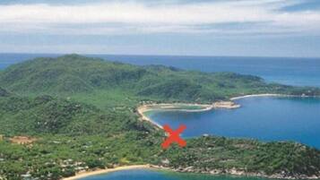 Experience the serene beauty of a natural coastline with lush green hills and a curving shoreline.