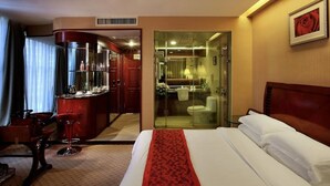 A hotel room with a bed, a red bar area, a bathroom with a glass partition, and a framed picture on the wall. - Hongfeng Hotel Shenzhen (SHENZHEN)