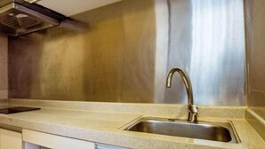 A kitchen with a stainless steel sink, a modern faucet, and a ventilation hood. - Hongfeng Hotel Shenzhen (SHENZHEN)