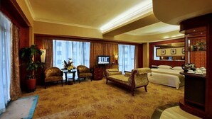A hotel room with a large bed, a sofa, two armchairs, a small table with a lamp, a TV, and a large window with curtains. - Hongfeng Hotel Shenzhen (SHENZHEN)