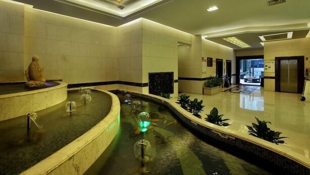 A modern lobby with a central water feature, a reception desk, and a reception area with a plant. - Hongfeng Hotel Shenzhen (SHENZHEN)