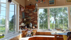 A cozy room with a brick wall, large windows, and a wooden bench. - Pension Hoshi Ni Negaiwo (Furano)