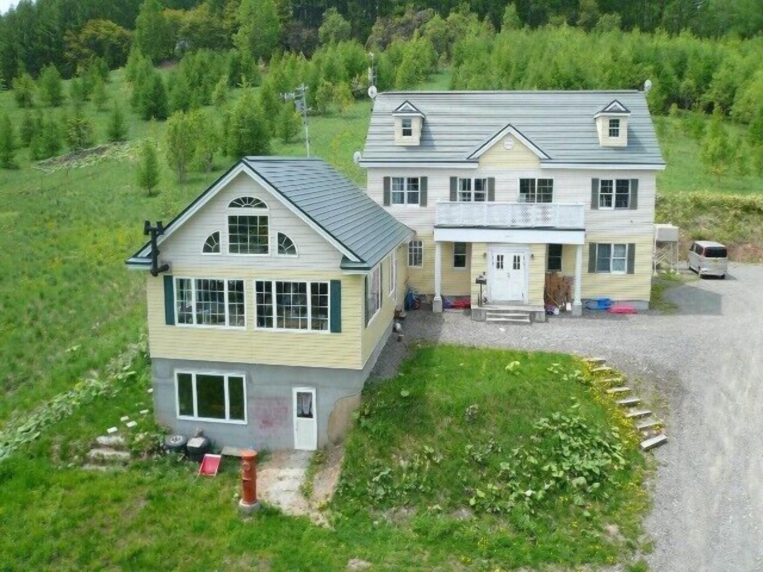 Une maison à deux étages avec un porche à l’avant et une allée.