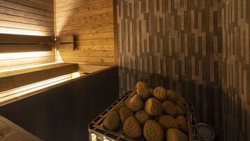 A sauna room with wooden walls, a bench, and a basket of stones.