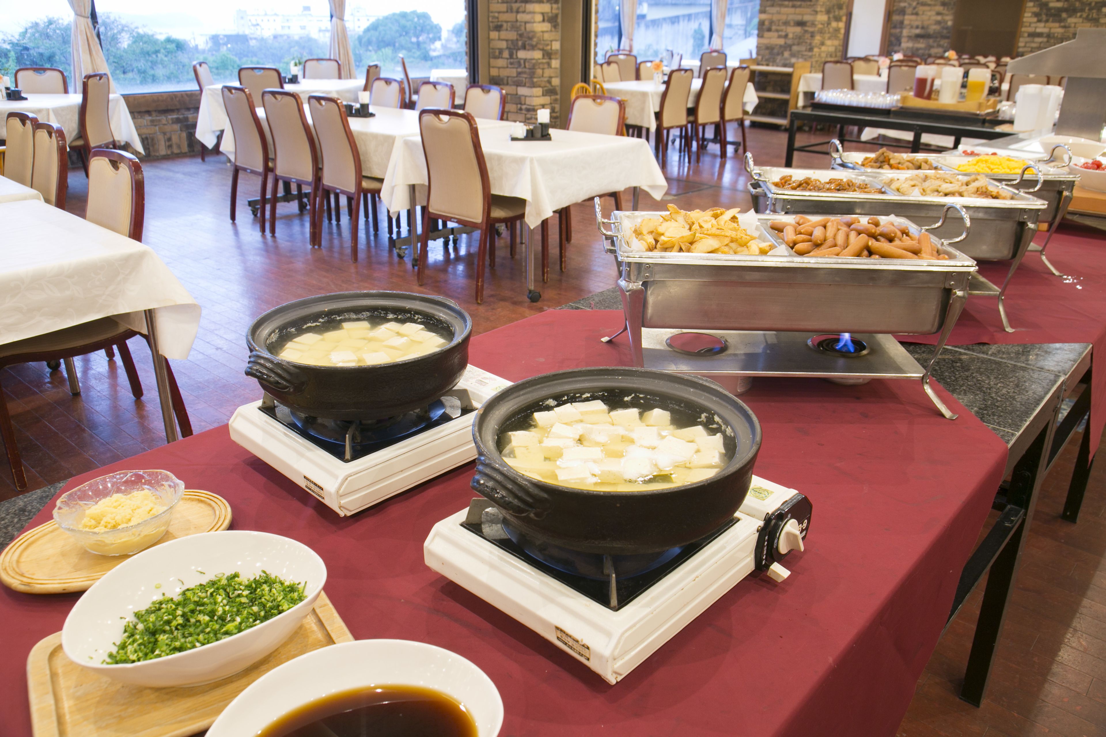 A buffet setup with various food items, including a hot pot and a buffet line with trays of food.