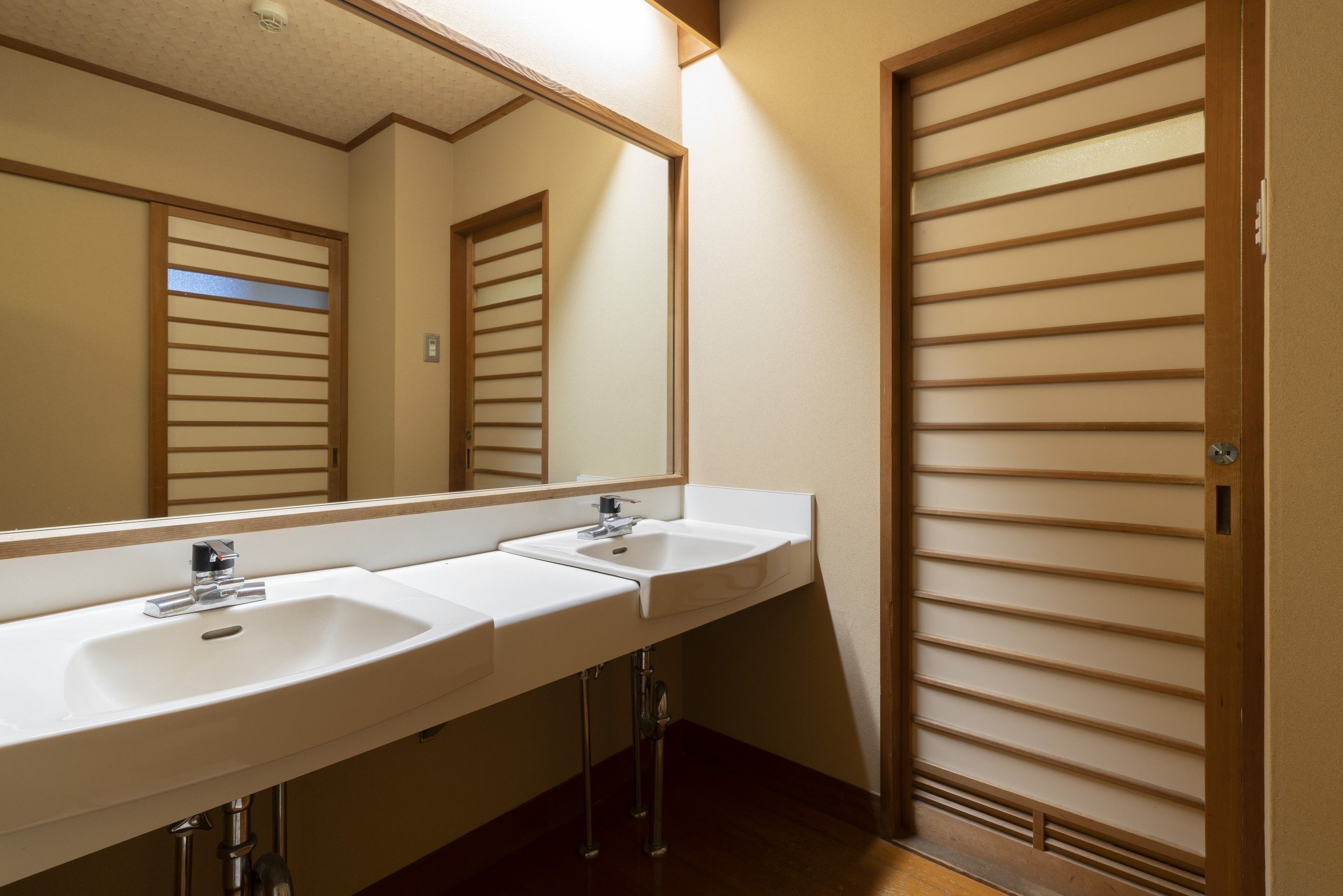 A bathroom with two sinks, a mirror, and a sliding door.