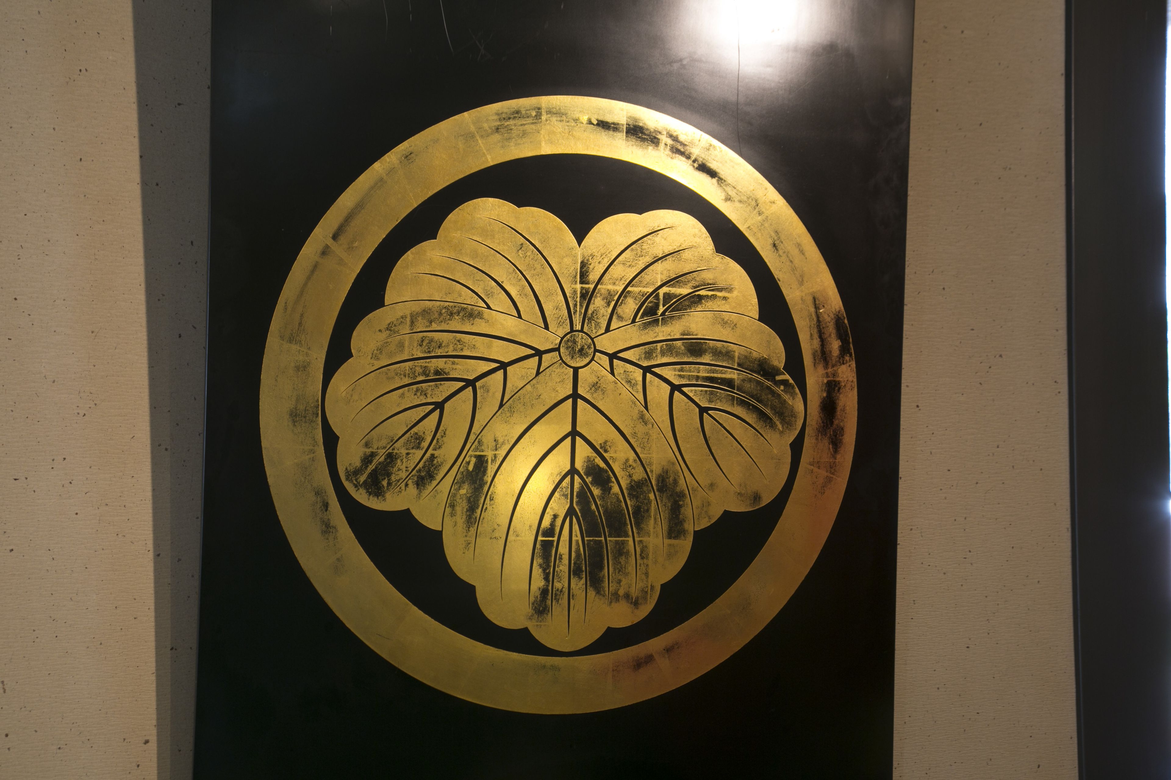 Ein goldenes, kreisförmiges Emblem vor schwarzem Hintergrund.