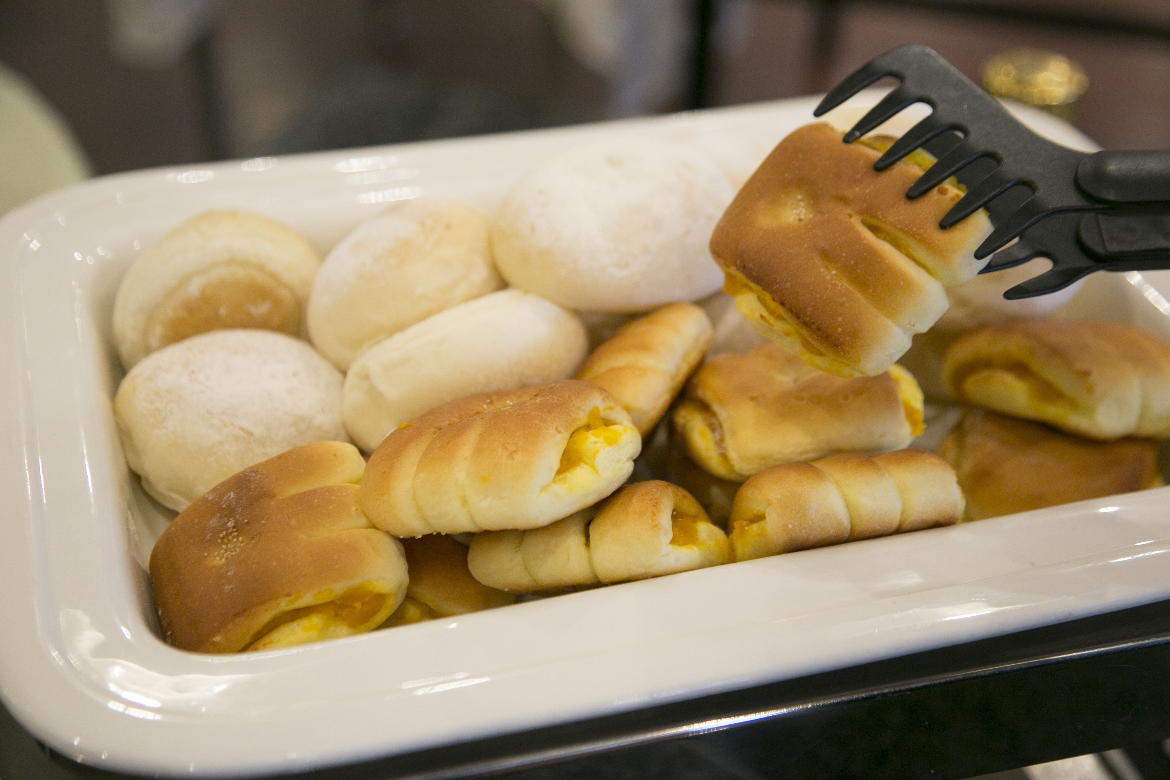 Una bandeja con bollos de desayuno, algunos rellenos de huevo.