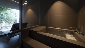 A modern bathroom with a glass-enclosed shower, a built-in bench, and a view of the outdoors. - Hiranoya (Gamagori)