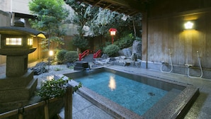 A traditional Japanese onsen with a stone pool, wooden structures, and a red bridge. - Hiranoya (Gamagori)