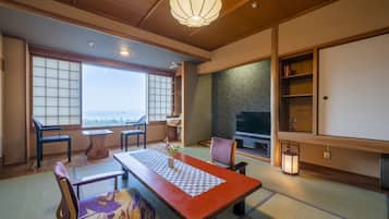 Een traditionele Japanse kamer met tatami vloerbedekking, een lage tafel met een decoratieve loper en een televisietoestel op een standaard.