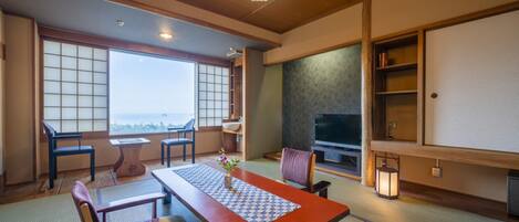 A traditional Japanese room with tatami flooring, a low table with a patterned runner, and a television on a stand.