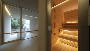 A modern interior with a sliding glass door leading to an outdoor area, a wooden wall with a built-in bench, and a ceiling with recessed lighting. - Hiranoya (Gamagori)