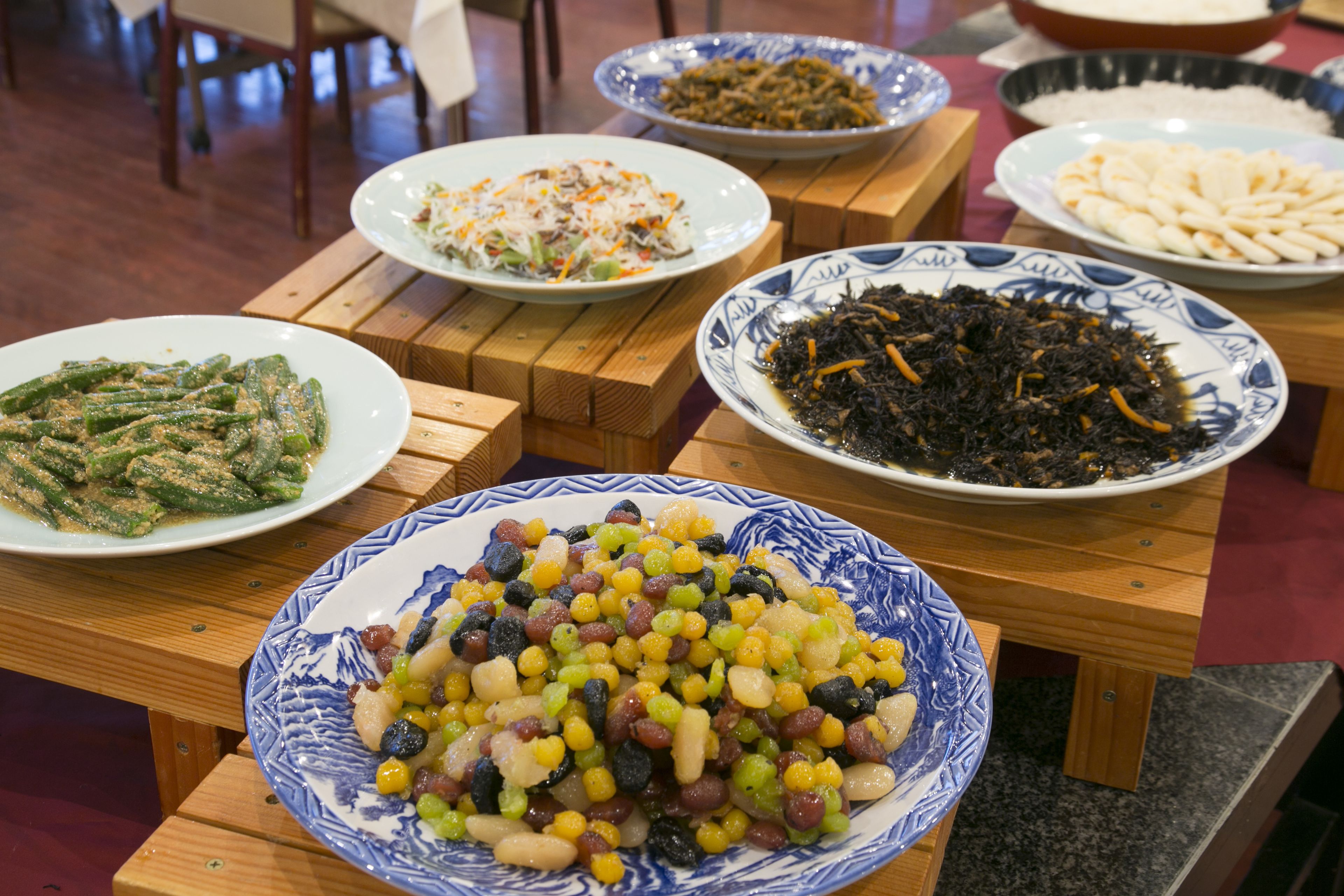 A table with various dishes including beans, greens, and a bowl of mixed vegetables.