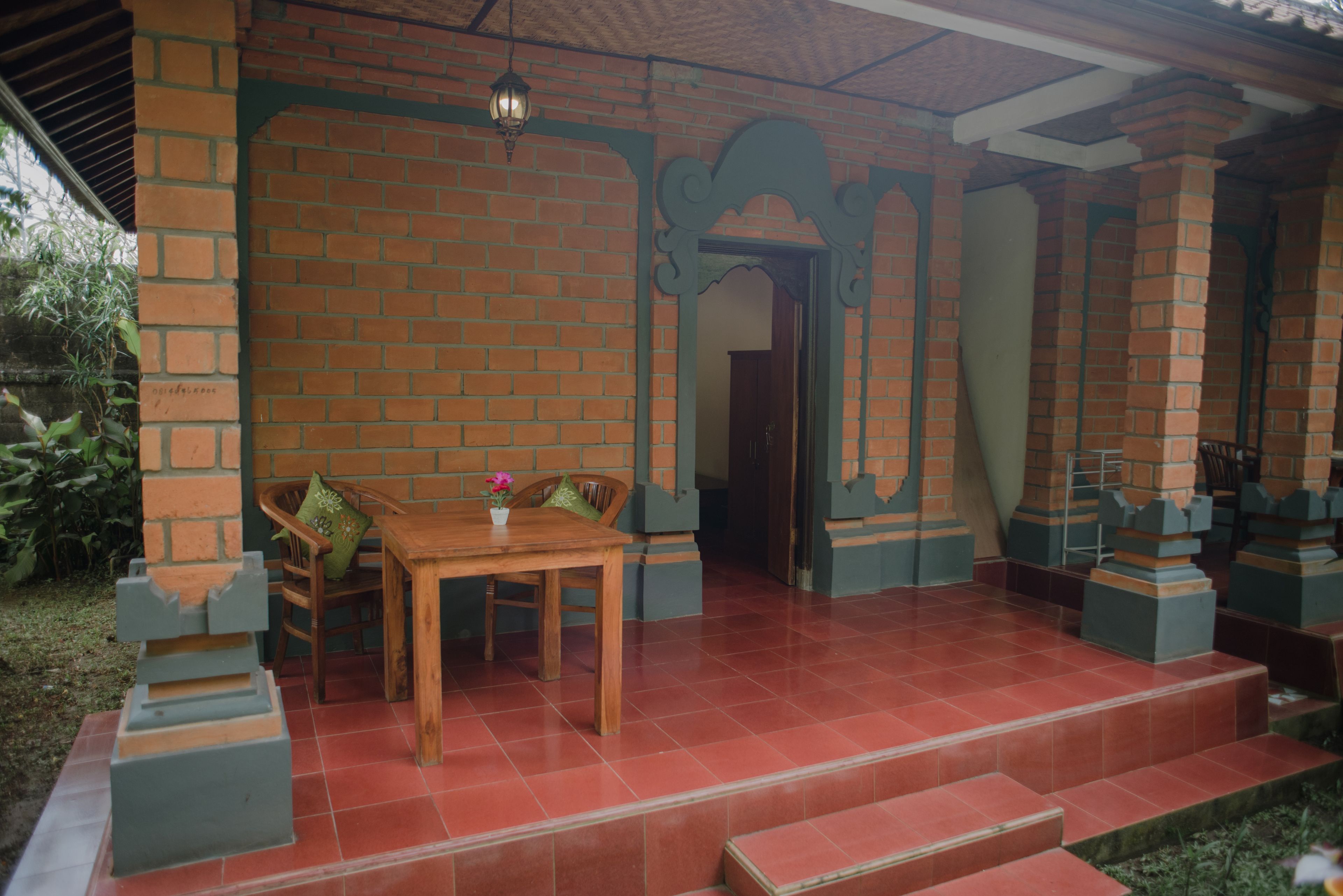 A covered patio area with a brick wall, a wooden table with chairs, and a small potted plant.