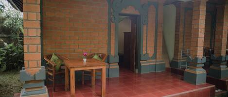 A covered patio area with a brick wall, a wooden table with chairs, and a small potted plant.