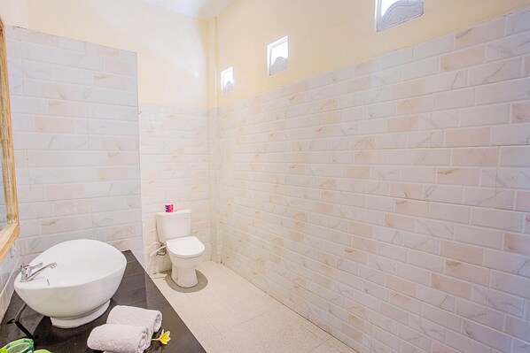 A bathroom with a white sink, toilet, and tiled walls.