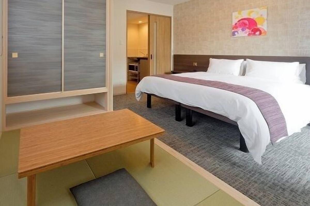 A hotel room with a bed, a desk, and a wardrobe.