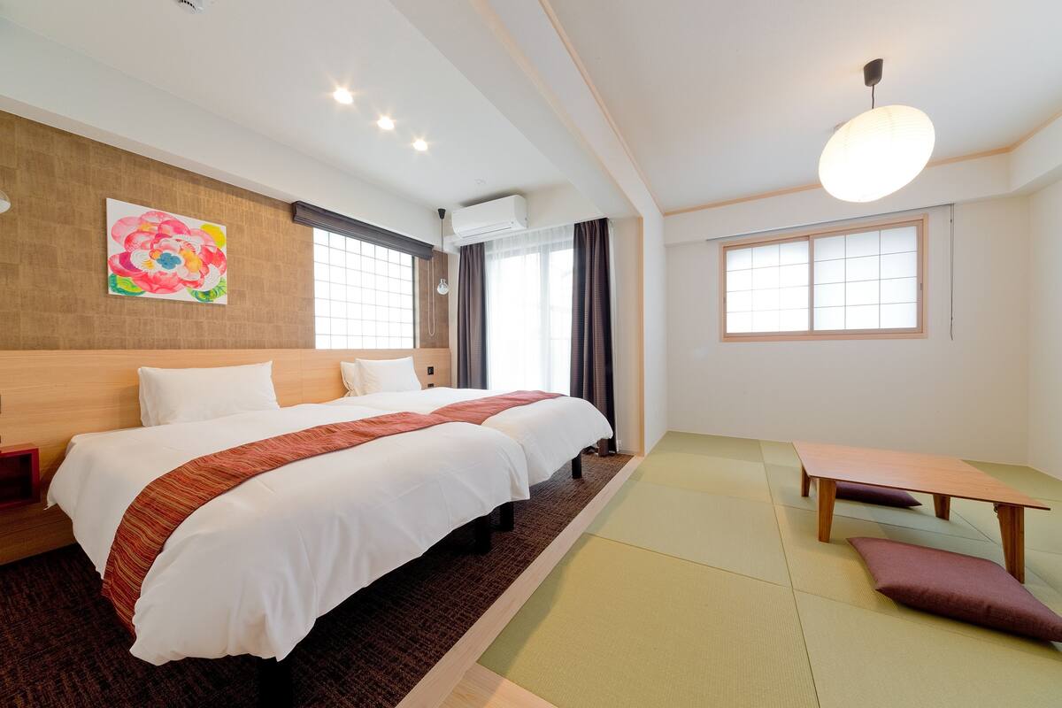 A hotel room with a large bed, a wooden headboard, a painting on the wall, and a window with curtains.
