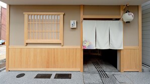 A traditional Japanese building with a wooden entrance, a sliding door, and a small lantern. - M’s Inn Higashiyama (Kyoto)