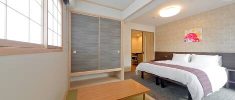 Une chambre d’hôtel avec un lit, une table en bois, un placard à portes coulissantes et un climatiseur fixé au mur.