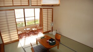 Une pièce traditionnelle japonaise avec un sol recouvert de tatamis, une table basse avec des coussins, un éventail et des portes coulissantes en papier de riz (shoji).