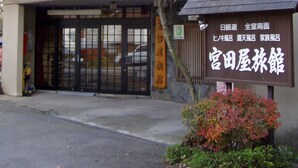Un bâtiment doté d’une entrée de style japonais traditionnel, d’une enseigne avec des caractères japonais et d’un arbre aux feuilles d’automne.